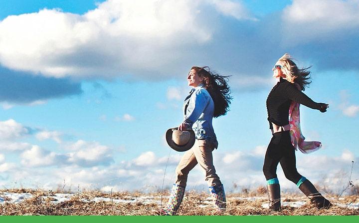 two women taking a wintertime stroll through a snowy field