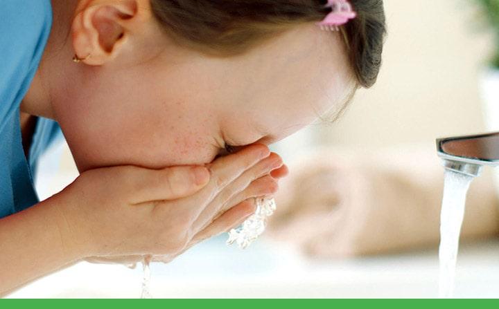 young girl washing her face at the bathroom sink
